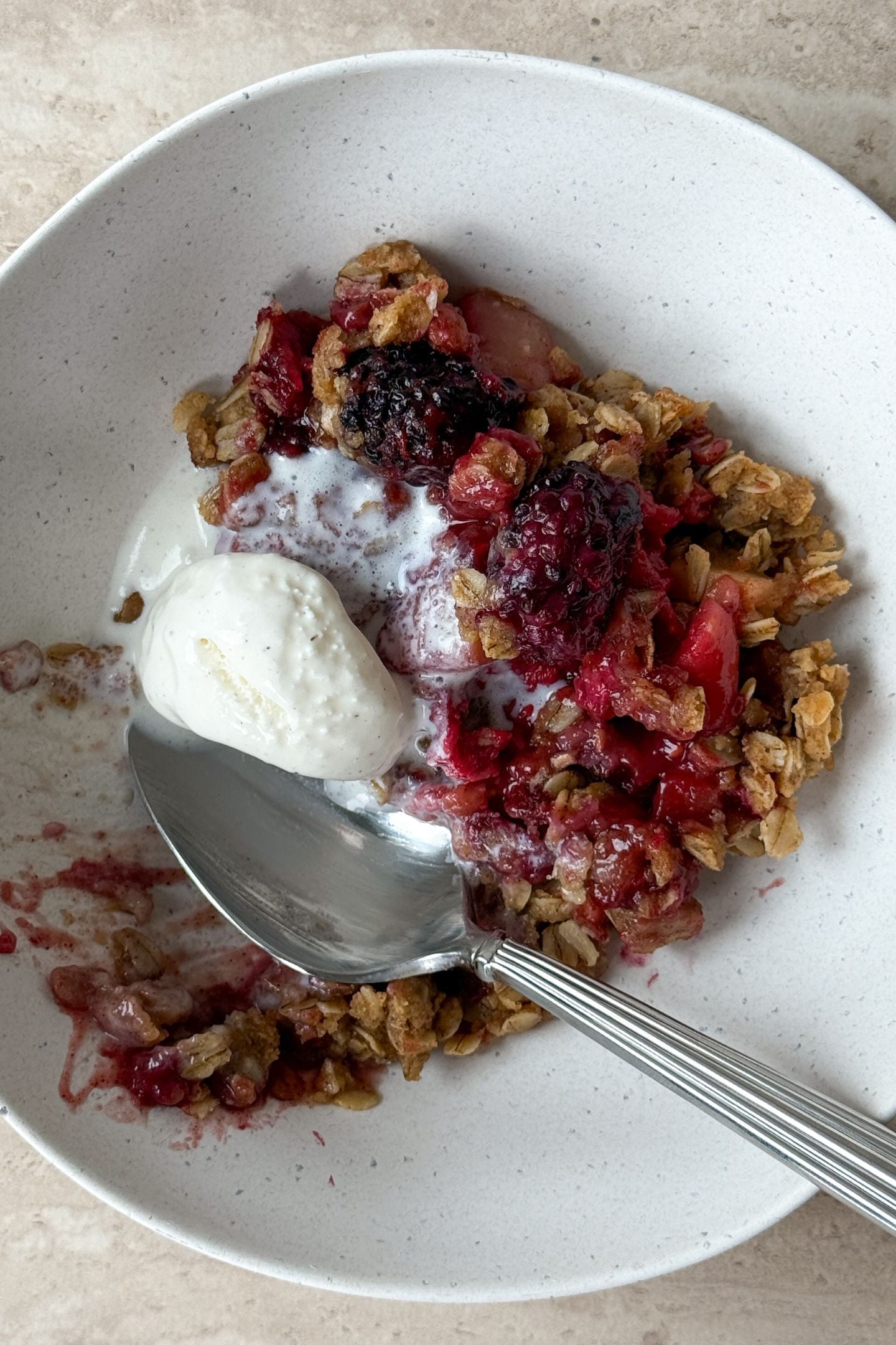 Eating the apple berry crisp with a spoon in the bowl.