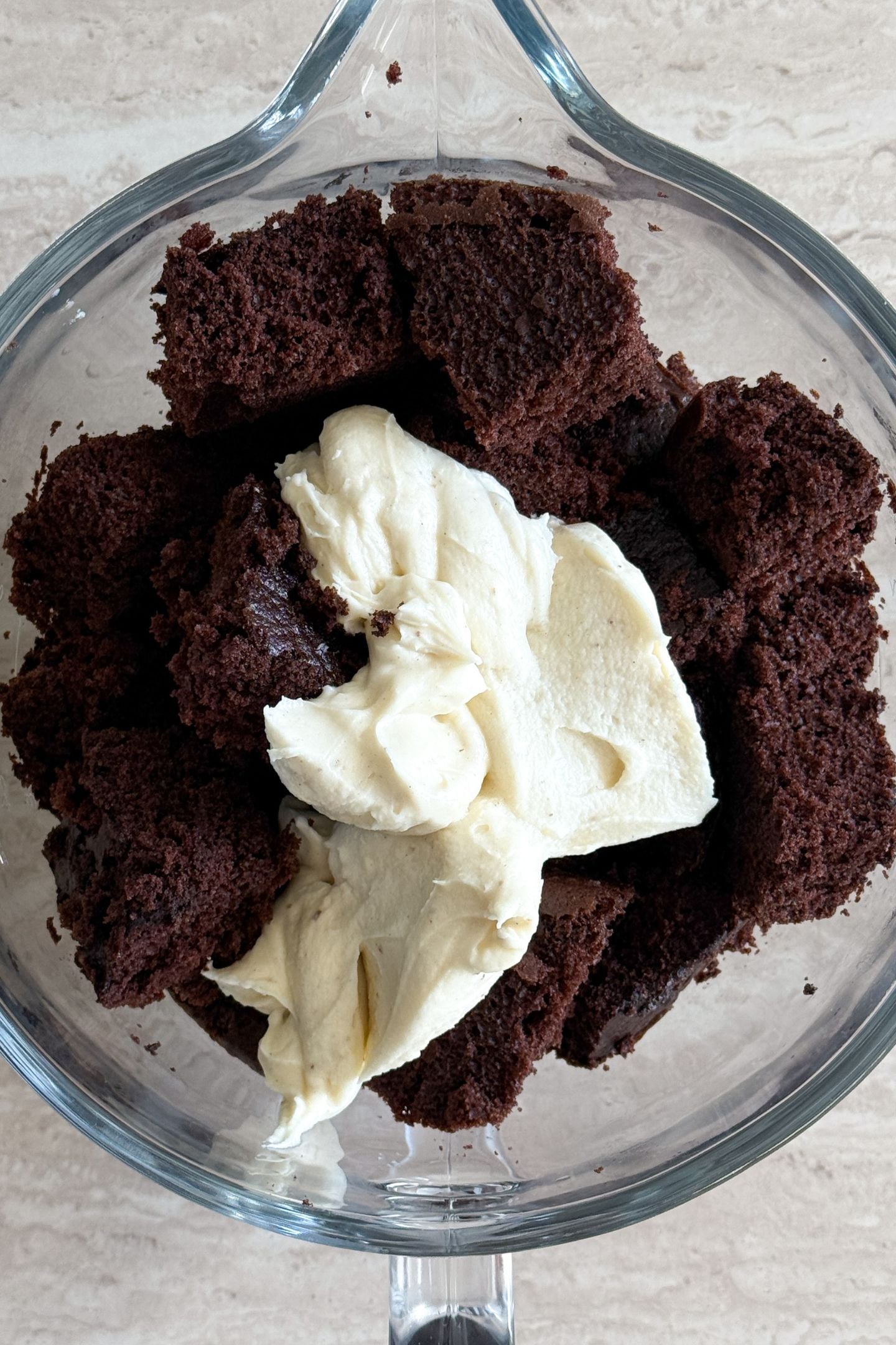 Baked and cooled cake in a mixing bowl with frosting.