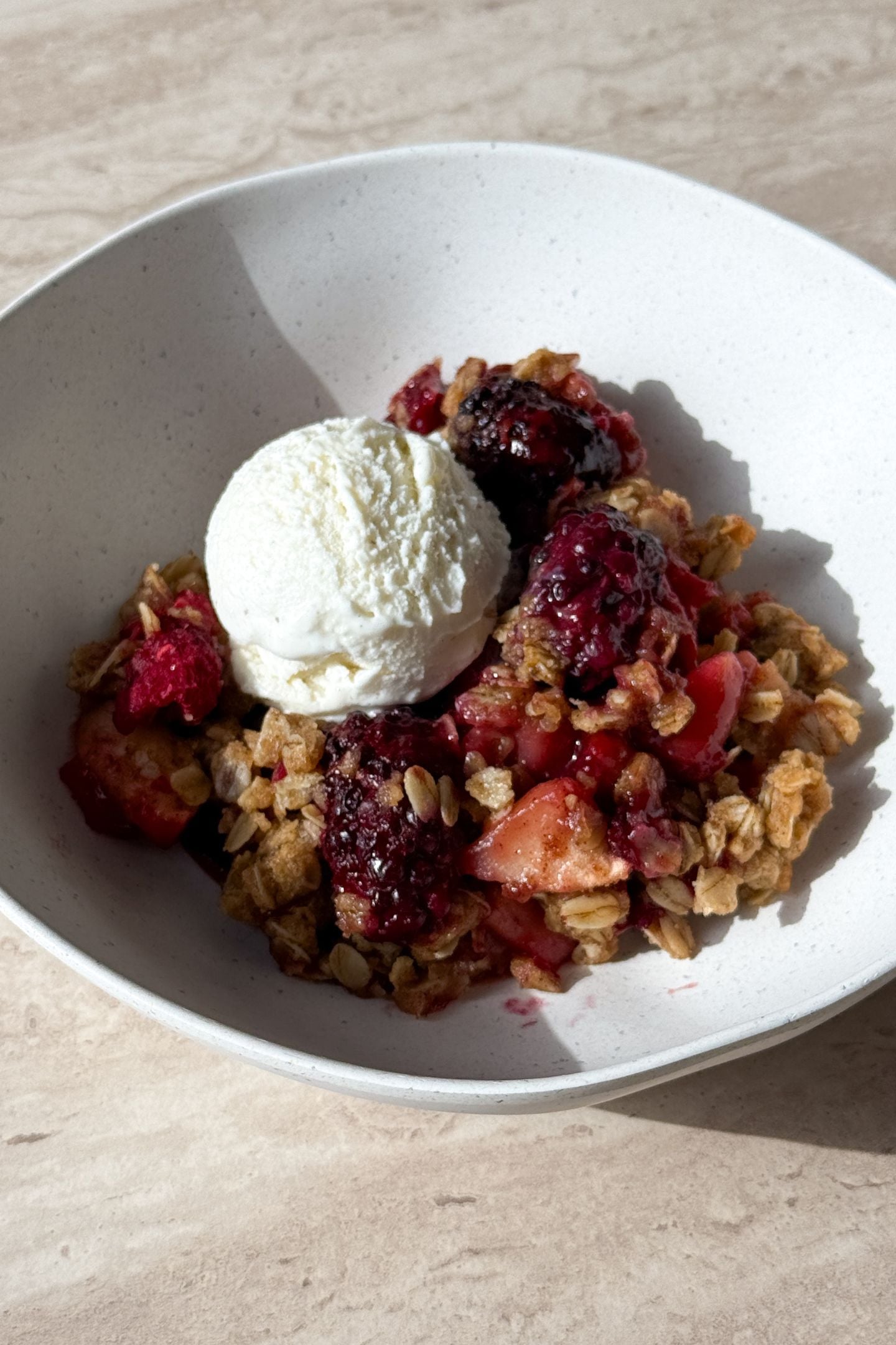 Topping the berry apple crisp with vanilla ice cream.