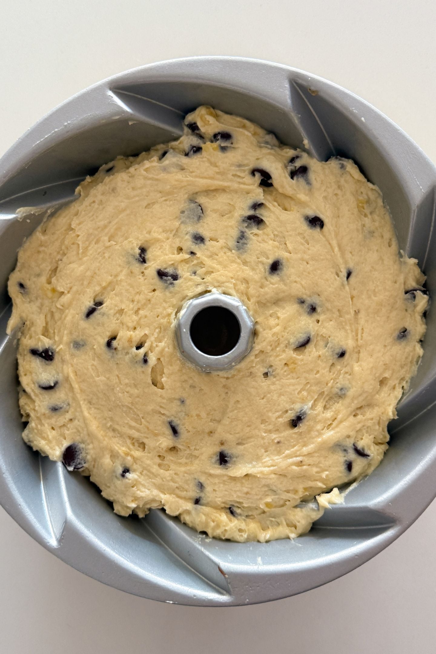 Cake batter added and spread in an even layer in the prepared bundt cake pan.