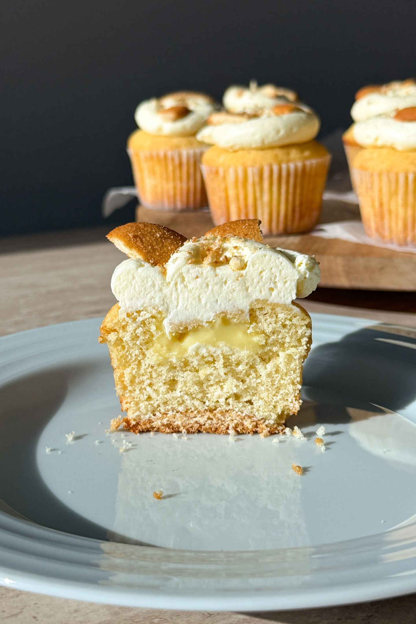 A banana pudding cupcake on a plate that is cut in half to show the inside filling and layers.