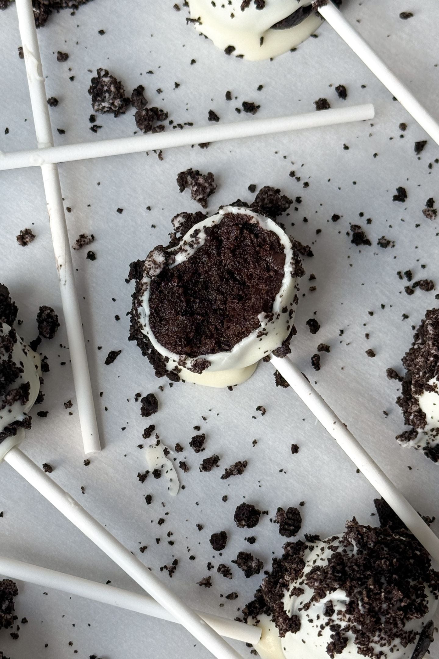 Oreo cake pop with a bite taken out of it on parchment paper.
