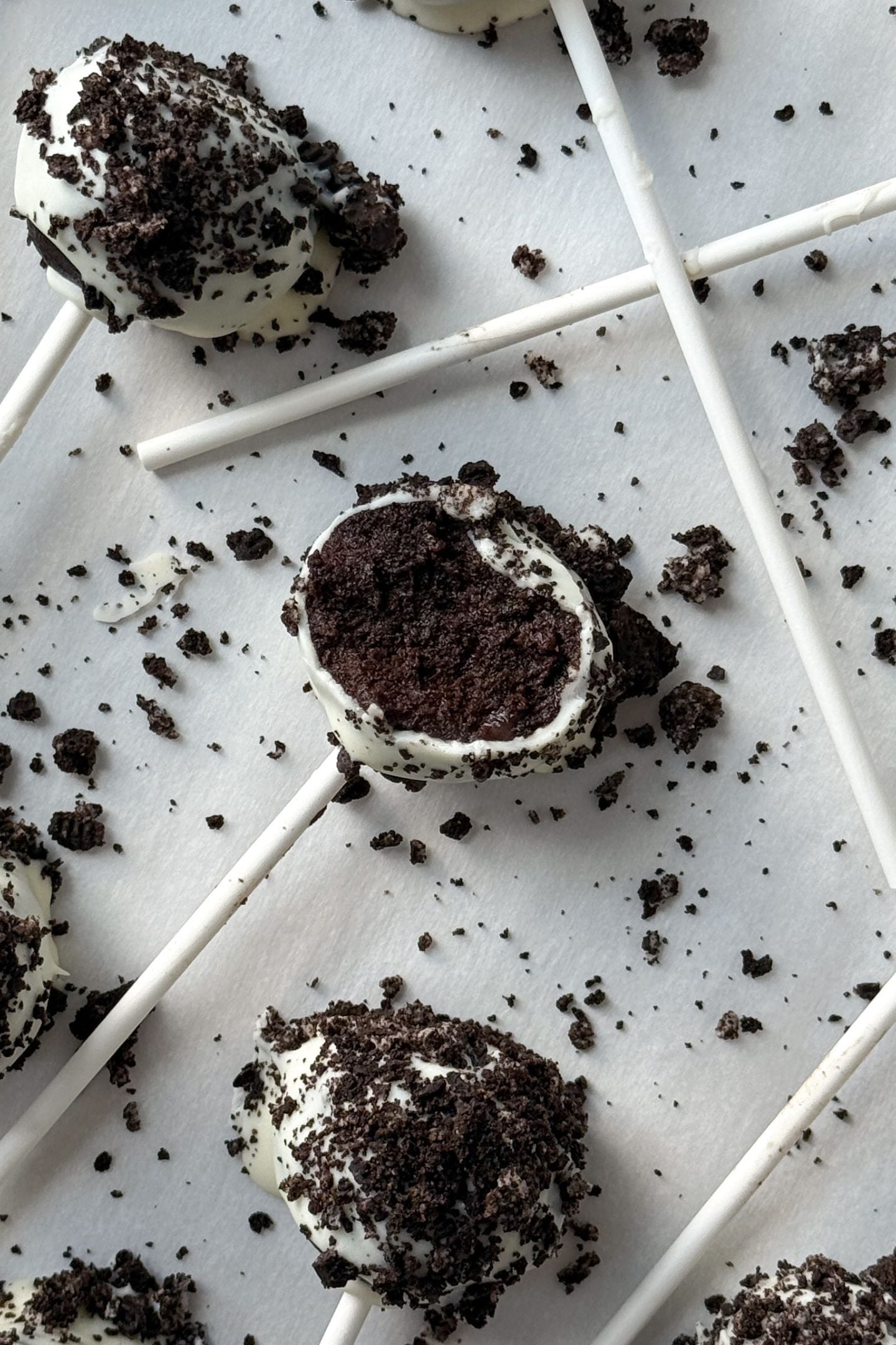Oreo Cake Pop with a bite taken out of it on parchment paper.