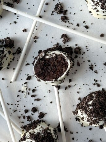 Oreo Cake Pop with a bite taken out of it on parchment paper.