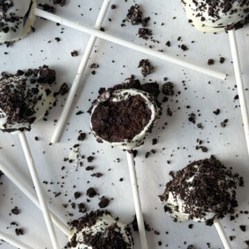 Oreo Cake Pop with a bite taken out of it on parchment paper.