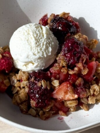 Apple Berry Crisp in a bowl with vanilla ice cream.