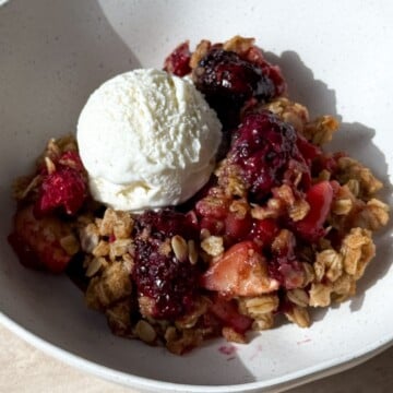 Apple Berry Crisp in a bowl with vanilla ice cream.